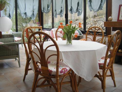 een tafel met stoelen en een vaas met bloemen erop bij Les Lutins in Sainte-Ruffine