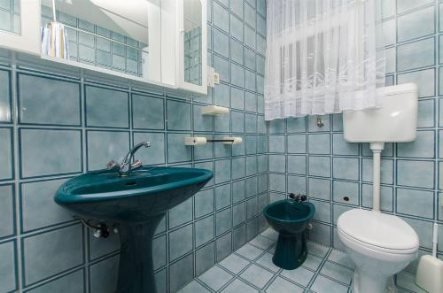 a blue tiled bathroom with a toilet and a sink at House Marija in Primošten