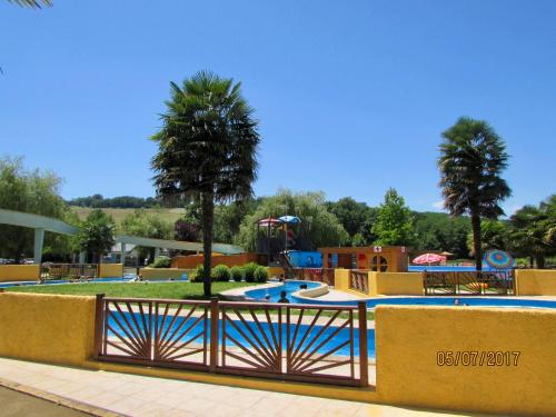 a pool in a park with a fence and trees at Les Gîtes de La Maison Bleue d'Estialescq in Estialescq