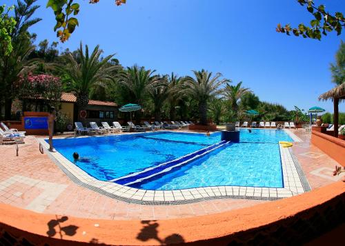 a large swimming pool in a resort with palm trees at Villaggio Athragon in Capo Vaticano