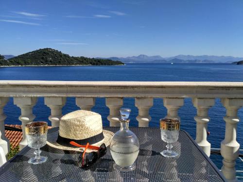 a table with glasses and a hat on a balcony at Apartments Šojka in Sobra