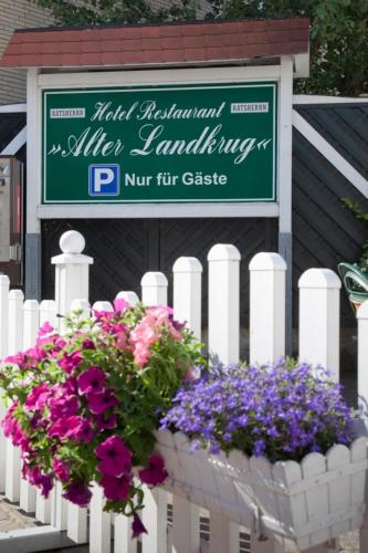 a white fence with flowers and a sign on it at Alter Landkrug in Nortorf