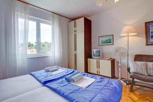 a bedroom with a bed with blue sheets and a window at Room Milka in Veli Lošinj