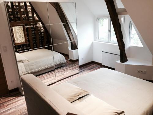 Cette chambre comprend un miroir, un canapé et un lit. dans l'établissement MAISON D'HÔTES LE HÊTREY, à Toutainville