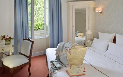 a bedroom with a bed and a chair and a window at Hôtel Le Plantagenet in Chinon