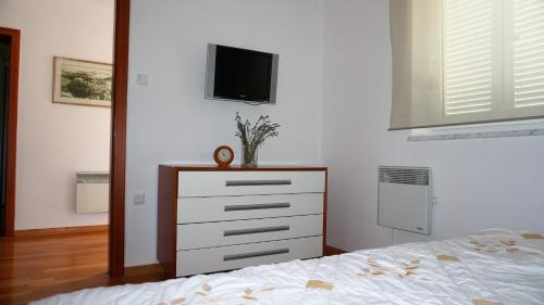 a bedroom with a bed and a dresser with a tv on the wall at Apartmani Gaj in Malinska