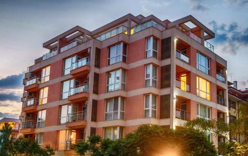 een hoog rood gebouw met een zonsondergang op de achtergrond bij Hotel Darius in Sunny Beach