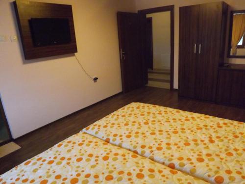 a room with a bed with a yellow and orange blanket at Dragoevata Kashta in Kotel
