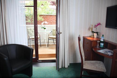a room with a chair and a desk and a door to a patio at Hotel Doberaner Hof in Bad Doberan