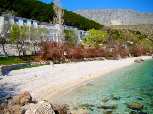 a beach in front of a building next to the water at Apartments Anka in Duće