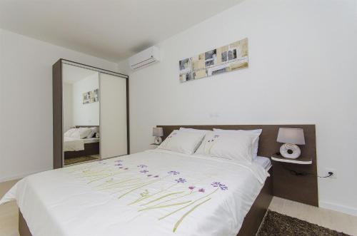 a bedroom with a large white bed with flowers on it at Apartments Villa V in Vir