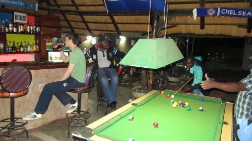 un grupo de hombres jugando al billar en un bar en Flintstones Backpackers en Lusaka