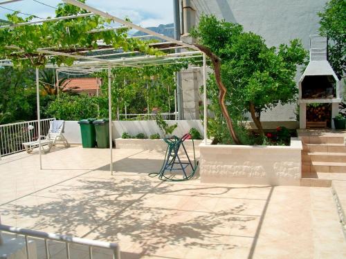 einen Garten mit einer Pergola, einem Tisch und Stühlen in der Unterkunft Apartment Ksenija in Drvenik