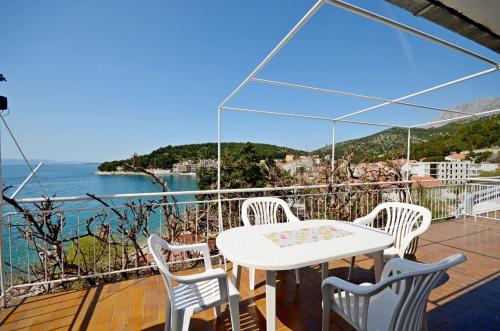 einen weißen Tisch und Stühle auf einem Balkon mit Meerblick in der Unterkunft Apartment Ksenija in Drvenik