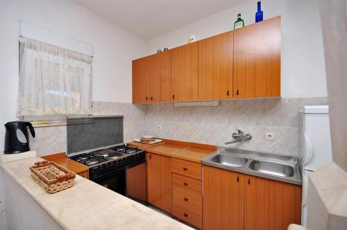 a kitchen with wooden cabinets and a stove and a sink at Apartment Katija in Postira