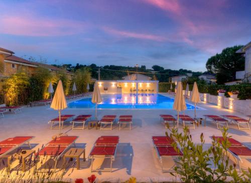 een zwembad met tafels, stoelen en parasols bij Hotel Giardino Suites&Spa in Numana