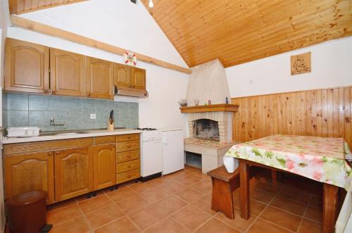 a kitchen with wooden cabinets and a table and a fireplace at House Krunoslav in Postira