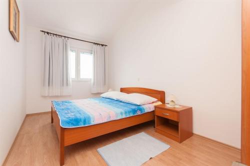 a bedroom with a bed and a nightstand and a window at Apartments Igor in Krvavica