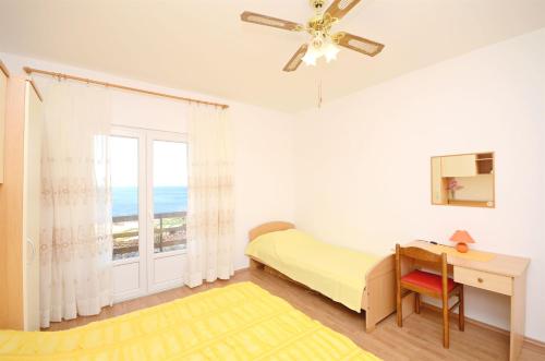 Un dormitorio con una cama y un escritorio y una ventana. en Apartments Marija, en Ivan Dolac