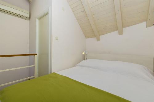 a bedroom with a white bed with a green blanket at House Gulliver in Kaštela