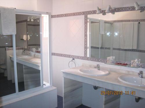 a bathroom with two sinks and a large mirror at Hotel Caballo Negro in Puerto Real