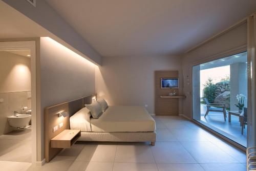 a bedroom with a bed and a bathroom with a balcony at Domu Simius Life Style Hotel in Villasimius