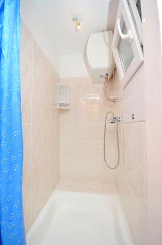 a bathroom with a shower with a white tub at Apartment Gordan in Murter