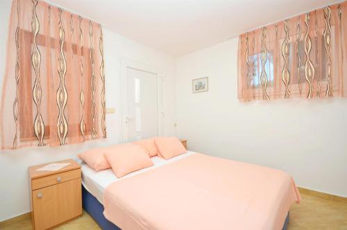 a bedroom with a bed with two pink pillows at Apartment Gordan in Murter