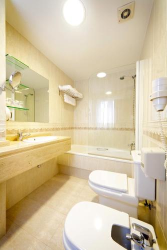 a bathroom with a toilet and a sink and a tub at Hotel Florida in Arteixo
