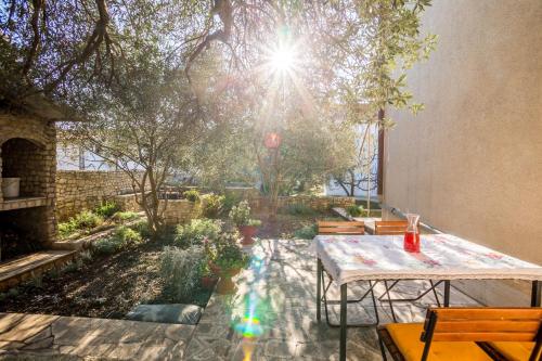 a patio with a table and chairs in a garden at Apartment Srecko in Vinišće