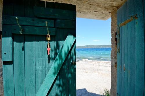 eine blaue Tür am Strand mit dem Ozean im Hintergrund in der Unterkunft House Mislav in Velike Kuknjare