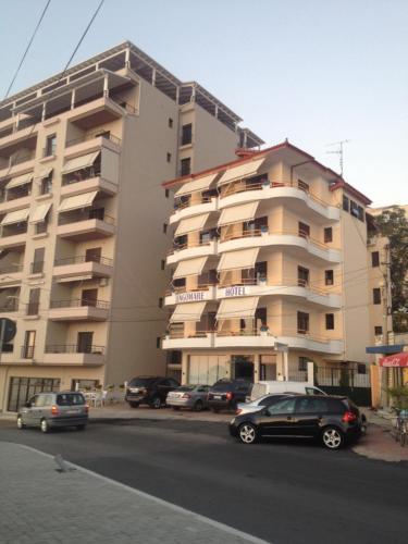 a large apartment building with cars parked in front of it at Hotel Lungomare in Vlorë