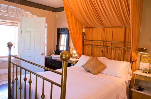 a bedroom with a bed with an orange curtain at Port Albert Inn and Cottages in Port Albert