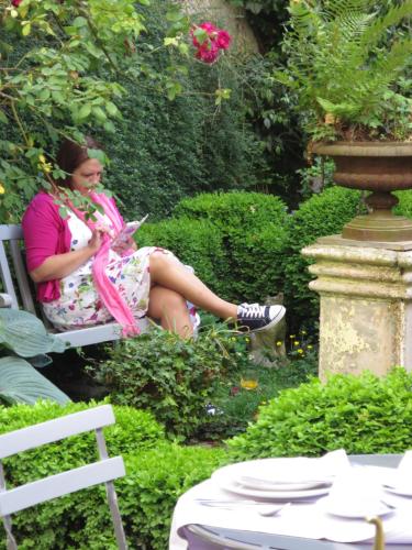 a woman sitting on a chair in a garden at Hotel Alegria in Bruges