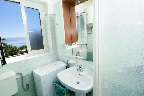 uma casa de banho com um WC, um lavatório e uma janela em Apartments Marijana em Ičići