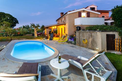 a swimming pool with two chairs and a table and a tablektop at House Poljica with a pool in Poljica