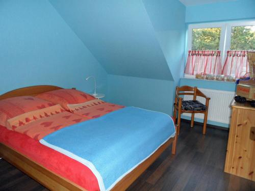 1 dormitorio azul con 1 cama y 1 silla en Ferienhaus Regenbogen, en Cuxhaven