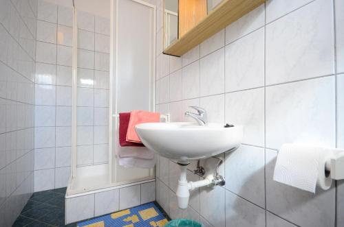 bagno bianco con lavandino e doccia di Rooms Mande a Banjol