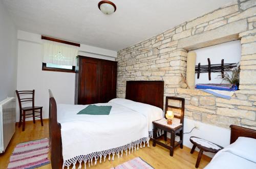 a bedroom with a large white bed and a stone wall at Apartment Srblin in Sveti Petar u Šumi