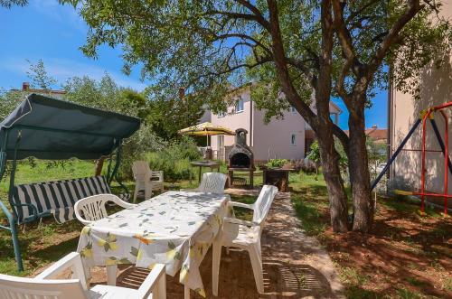 a table and chairs under a tree in a yard at Apartments Dragica in Štinjan