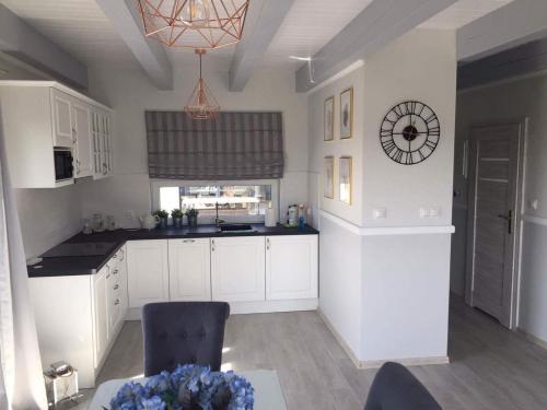 a kitchen with white cabinets and a clock on the wall at Nadmorski Zaułek in Jastrzębia Góra