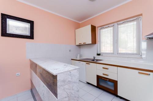 RakaljにあるApartments Milanのピンクの壁と白いキャビネット、シンク付きのキッチン
