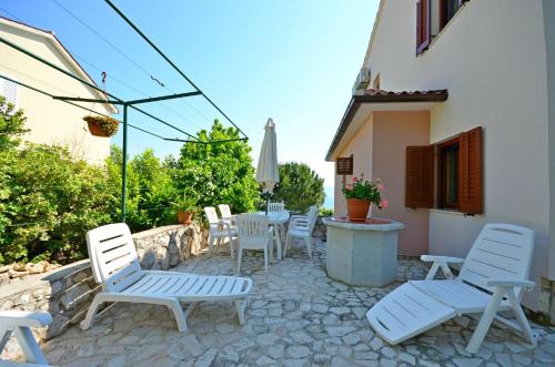 a patio with white chairs and a table and an umbrella at Apartment Andreas in Ravni