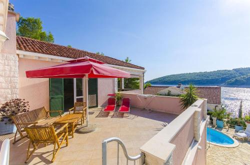 a patio with a table and chairs and an umbrella at Villa Rosada in Vela Luka