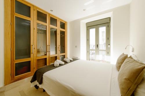 a bedroom with a large white bed with wooden cabinets at 1E Azofaifo St Apartment in Seville