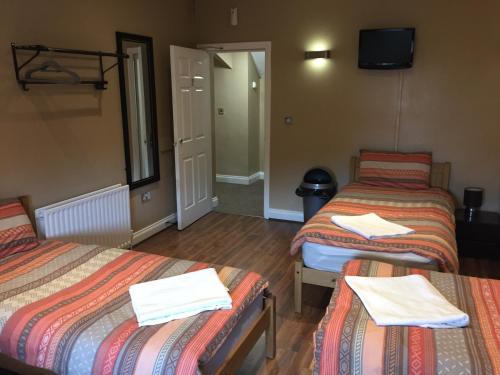 
a hotel room with two beds and a desk at Anfield Accommodation part of The Twelfth Man Public House in Liverpool
