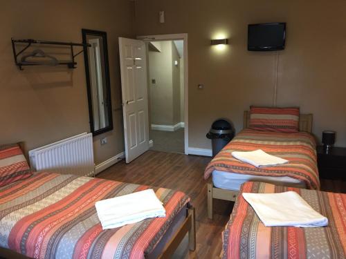 a hotel room with two beds and a television at Anfield Accommodation part of The Twelfth Man Public House in Liverpool