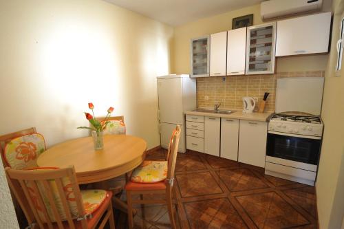 a small kitchen with a wooden table and a table and chairs at Apartments Šojka in Sobra
