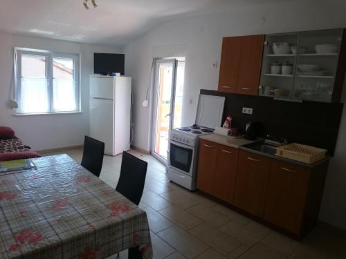 eine Küche mit einem Tisch und eine Küche mit einem Kühlschrank in der Unterkunft Apartmani Bartolić in Biograd na Moru