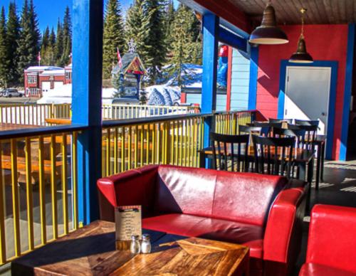 a red leather couch sitting on a porch with tables and chairs at The Bulldog Hotel in Silver Star